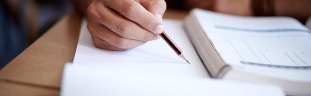 a hand holding a pencil hovering over pieces of paper